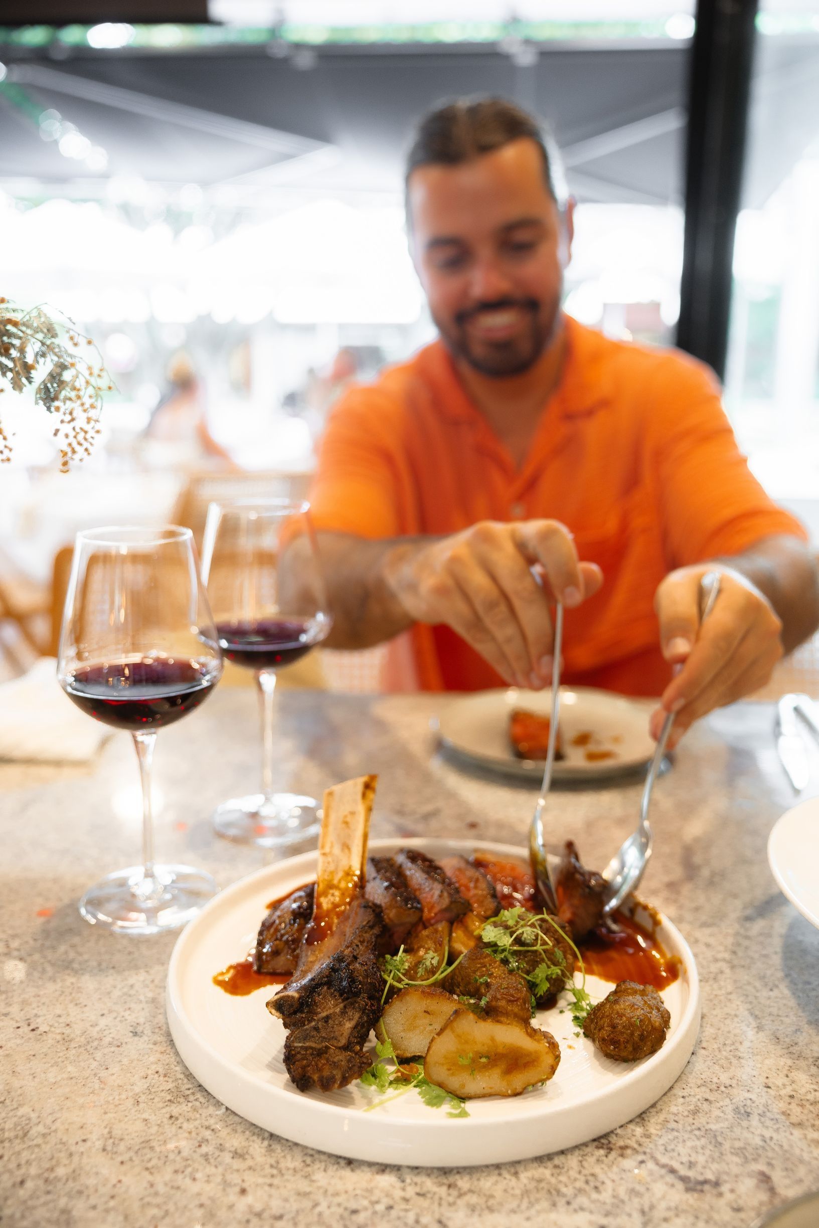 Man serves a portion of steak onto his plate while dining at a restaurant Man serves a portion of steak onto his plate while dining at a restaurant