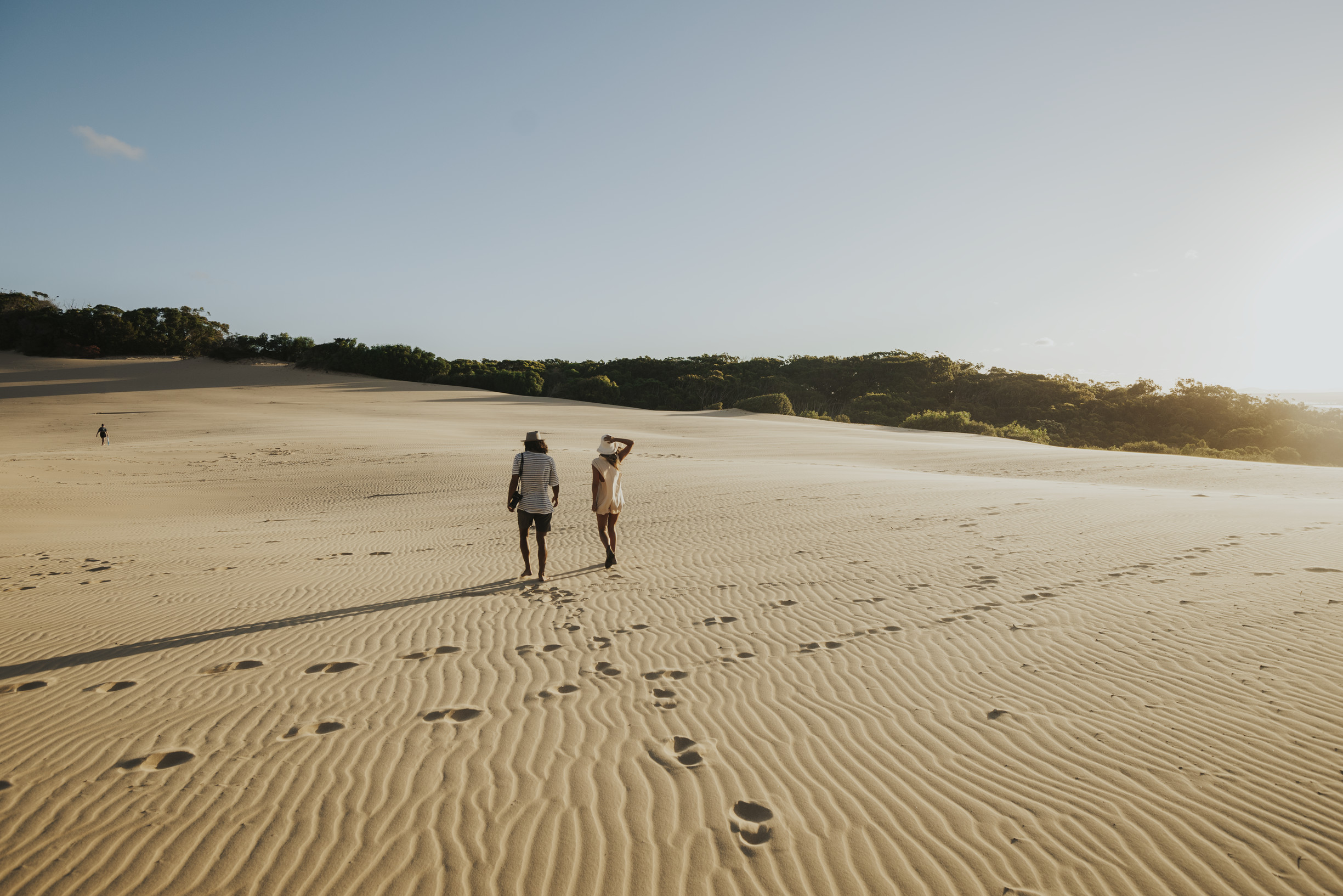 Couple walking across the sand dunes of Carlo Sand Blow near Rainbow Beach Couple walking across the sand dunes of Carlo Sand Blow near Rainbow Beach