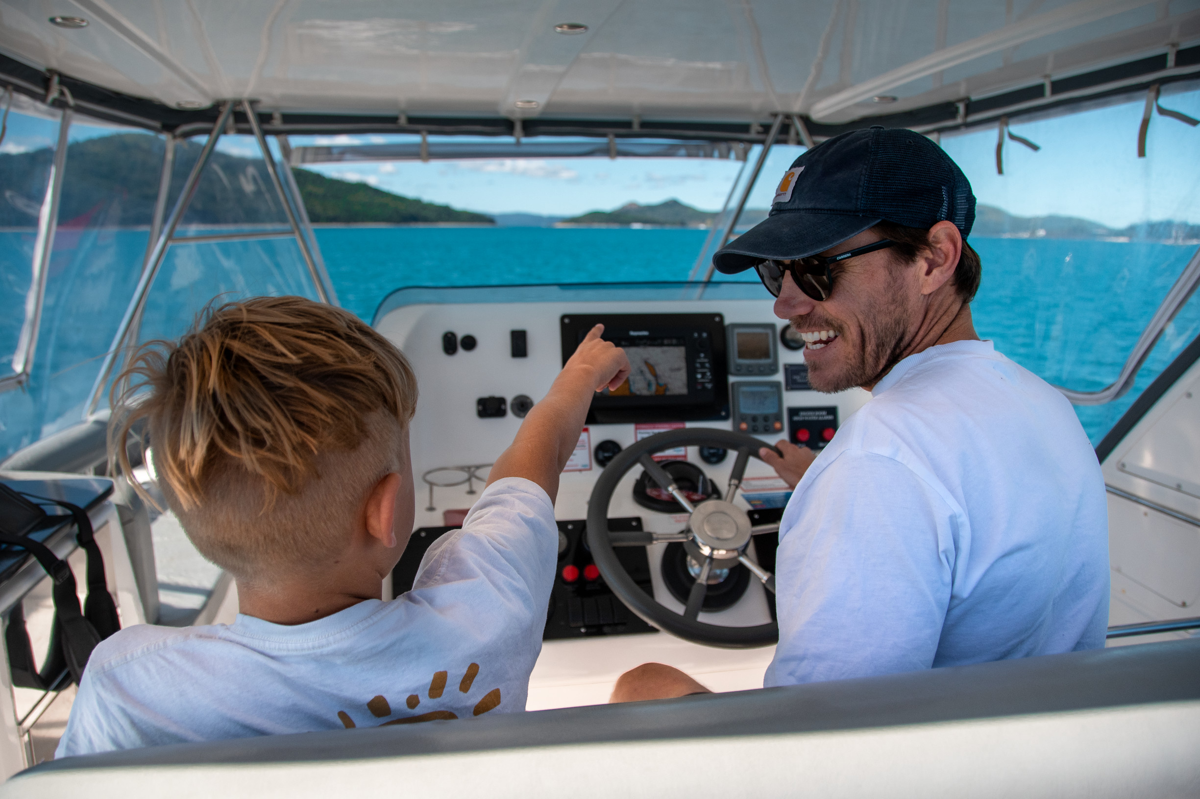 Father and son on board a bareboat charter | family sailing holiday whitsundays Father and son on board a bareboat charter | family sailing holiday whitsundays