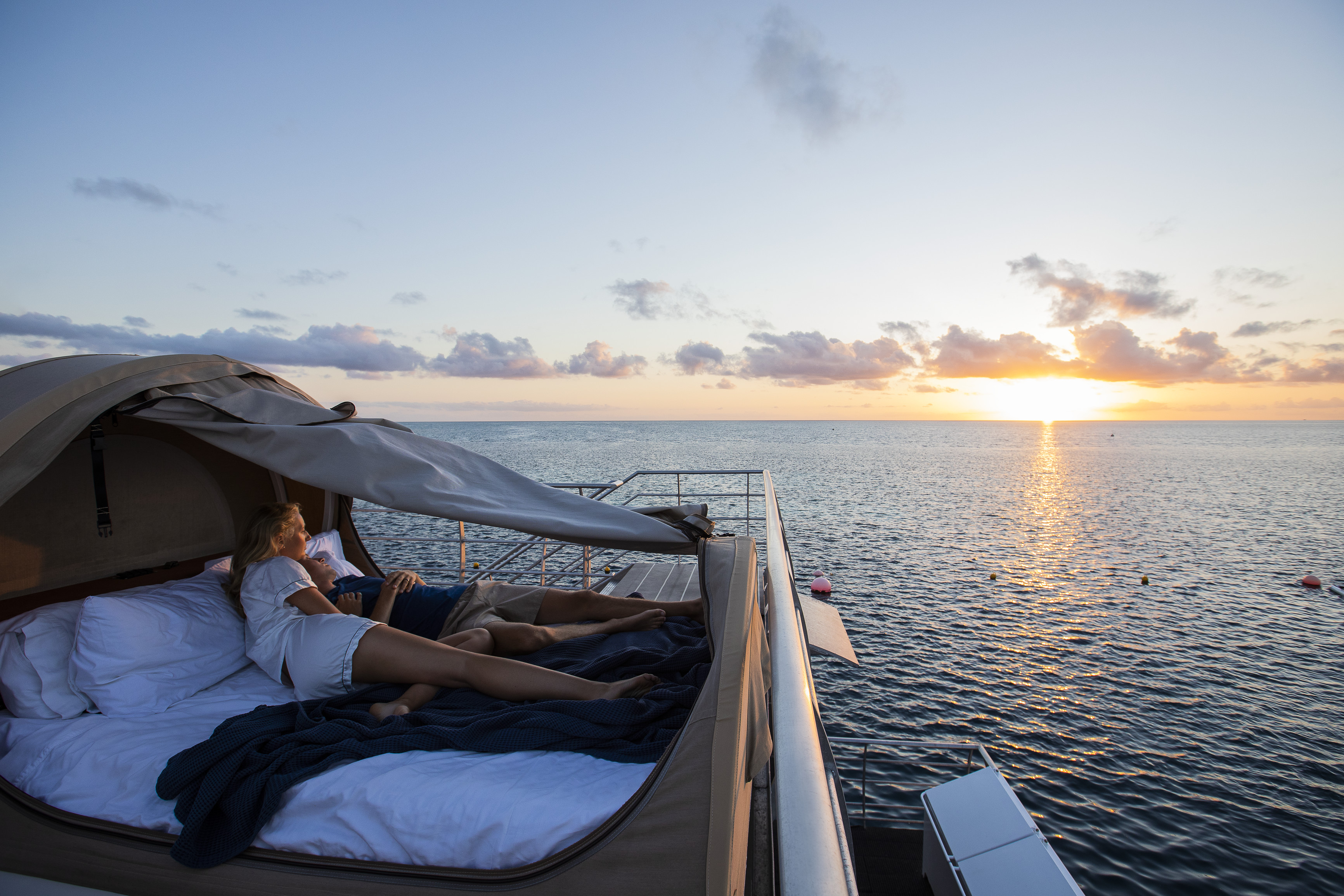 Couple watching the sun set, while laying in their reefbed, as part of the Reefsleep experience with Cruise Whitsundays | Great Barrier Reef tours Couple watching the sun set, while laying in their reefbed, as part of the Reefsleep experience with Cruise Whitsundays | Great Barrier Reef tours