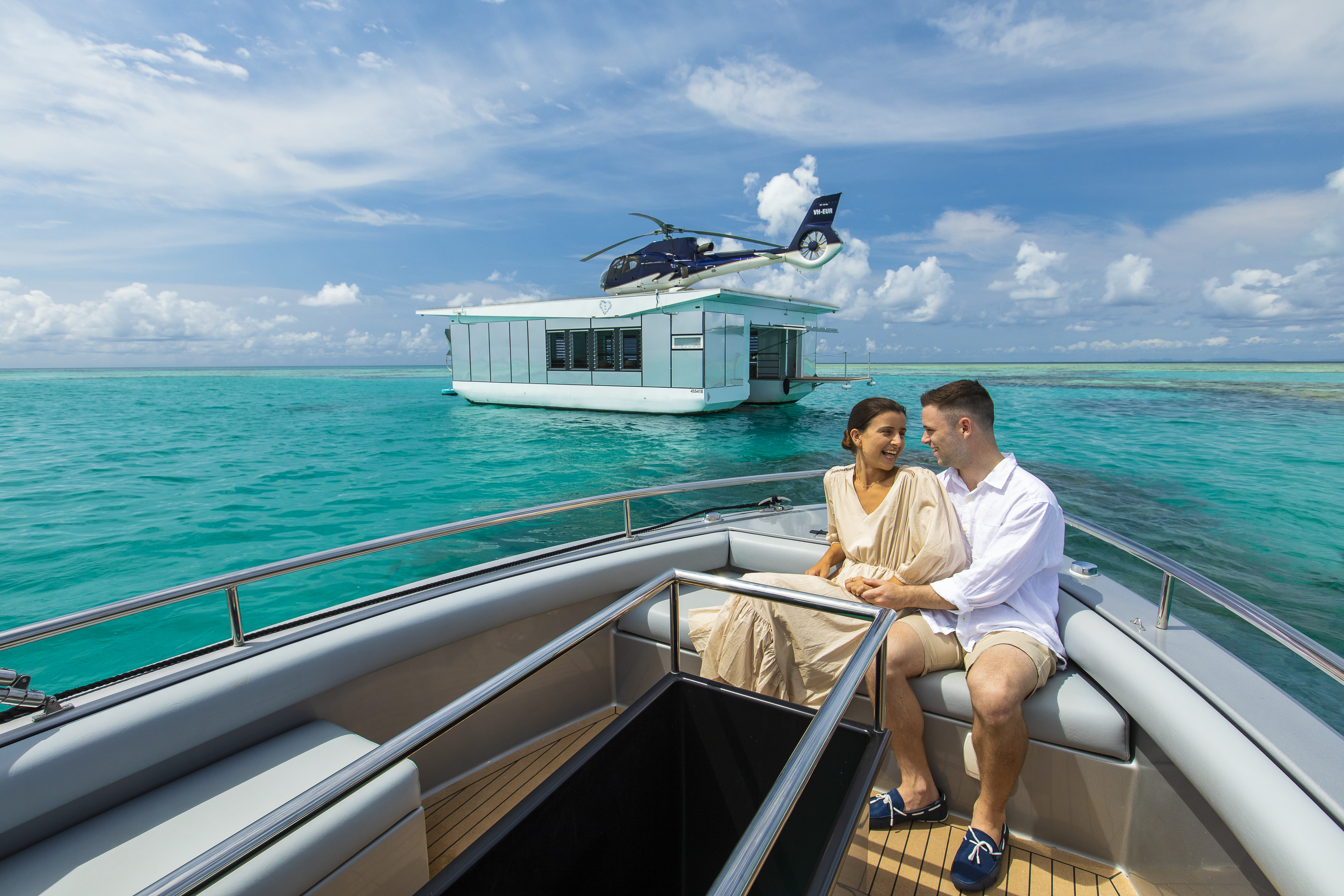 Couple relax on boat near pontoon in middle of reef