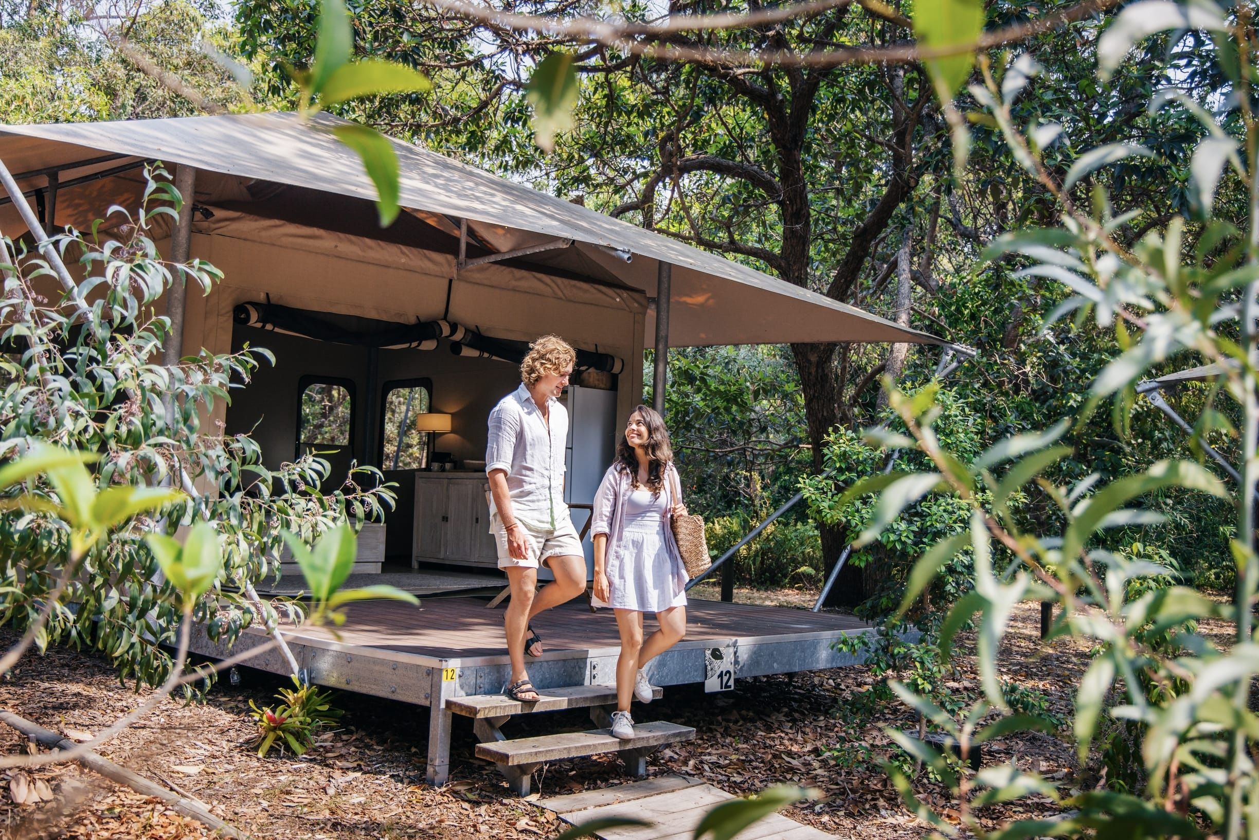 Couple walk out of their glamping tent in the bush