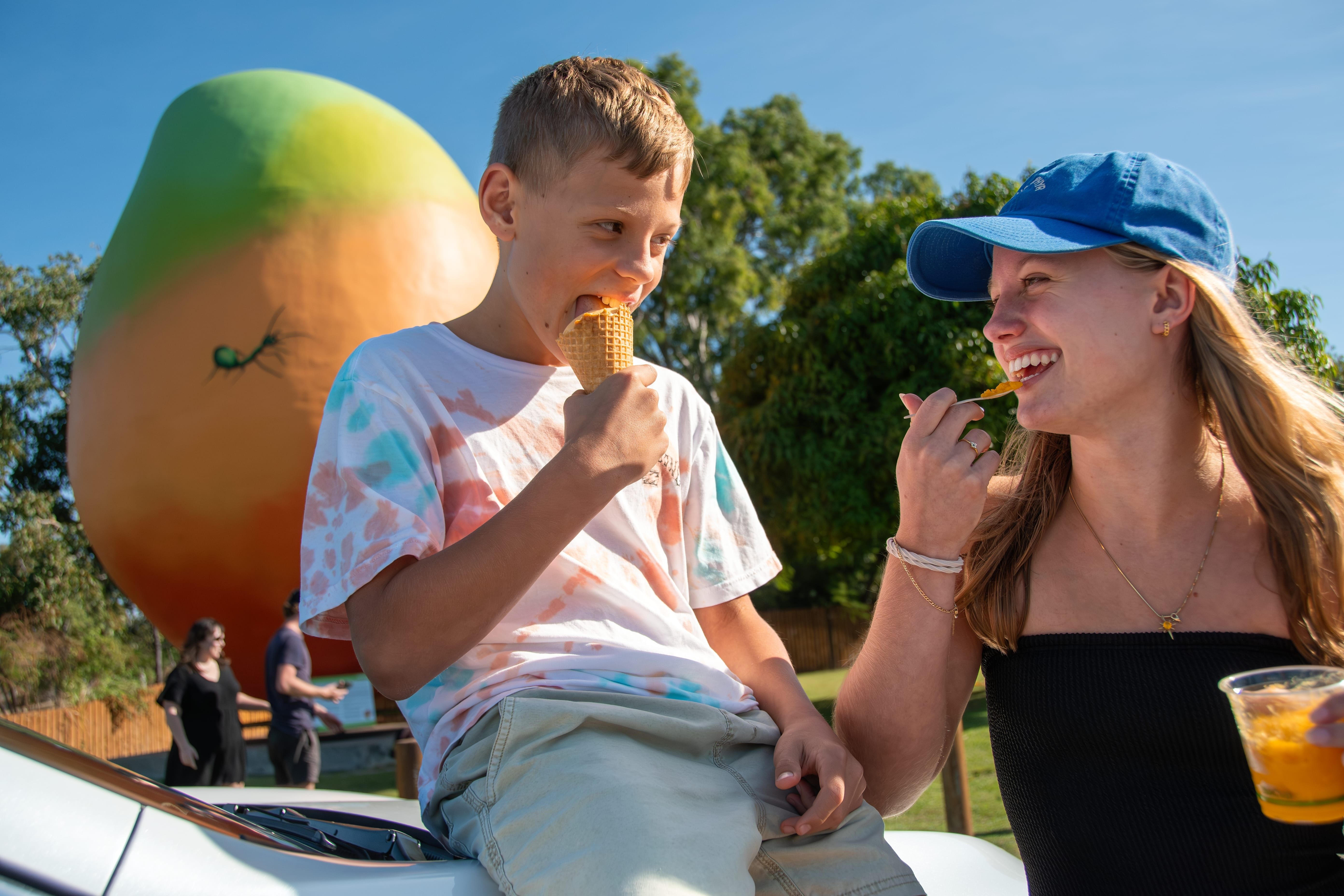 Kids in front of the Big Mango enjoying a mango fruit treat in Bowen