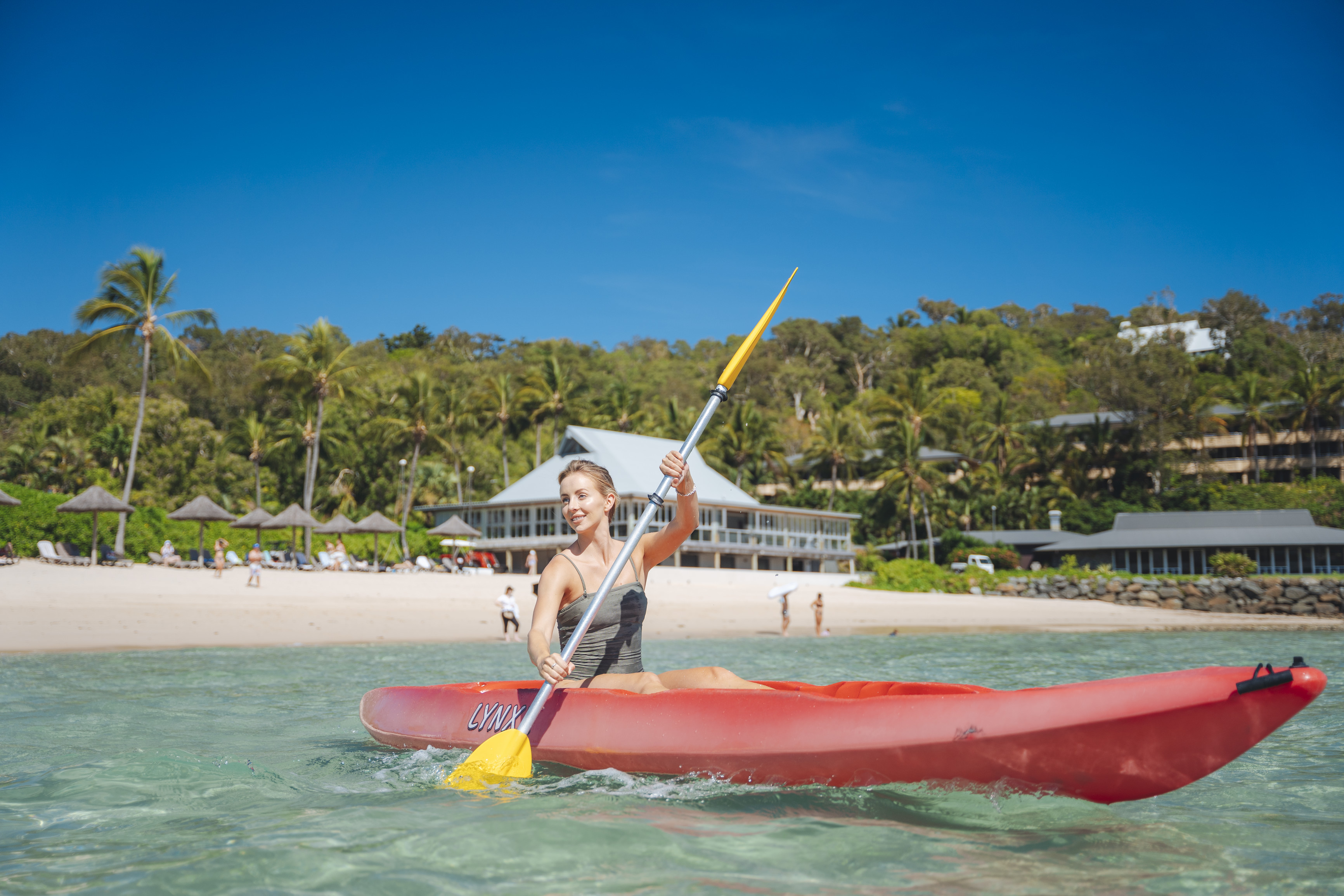 Woman kayaking off beach on a tropical island
