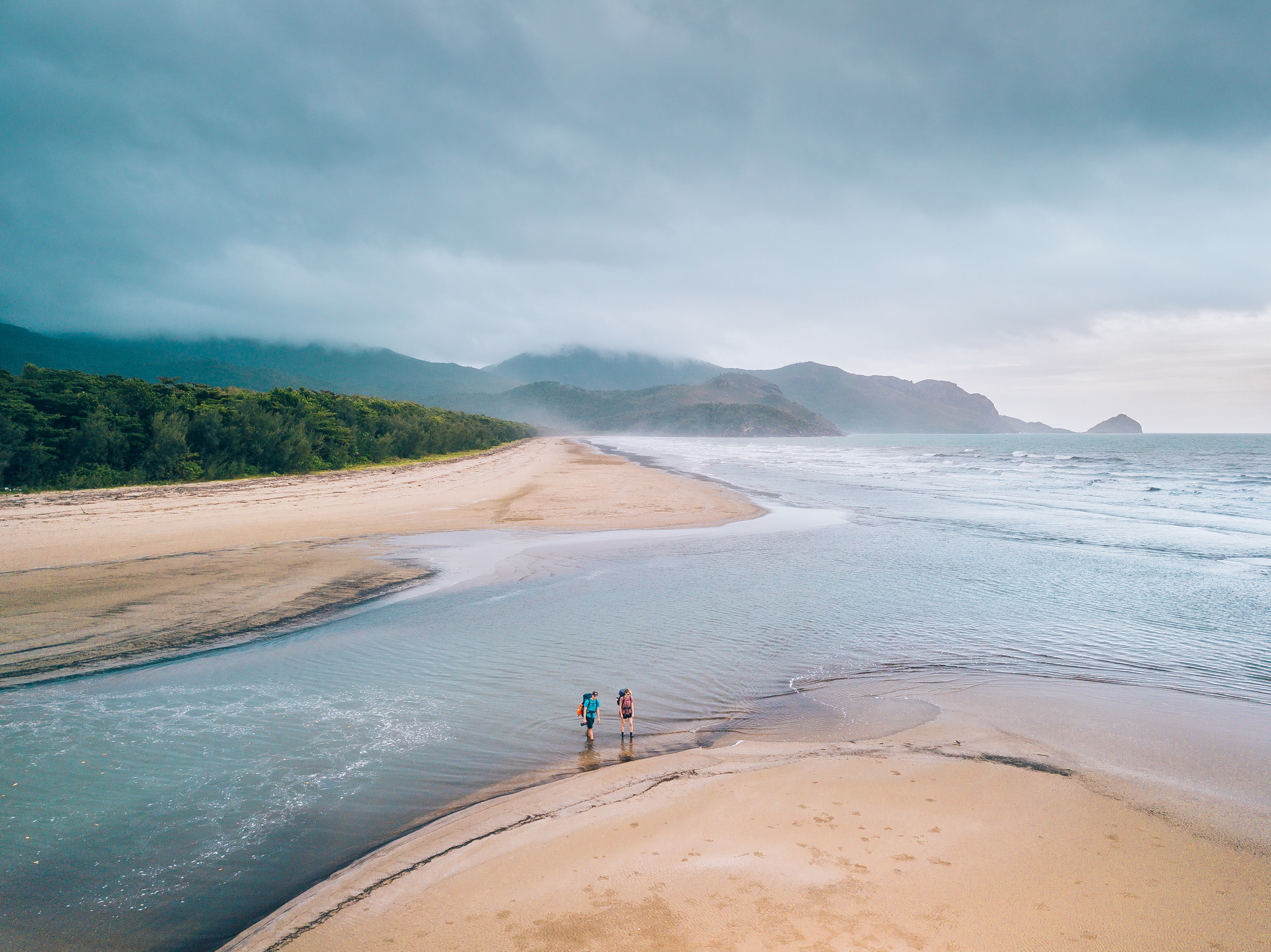 Two hikers cross a tidal channel on an island walking trail Two hikers cross a tidal channel on an island walking trail