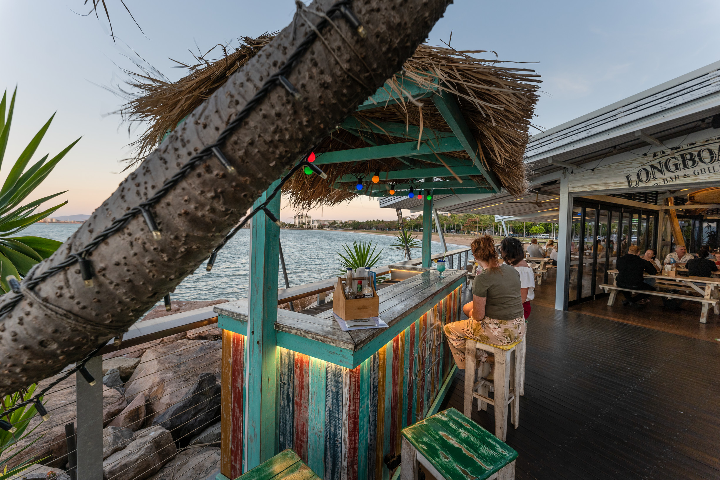 Two women sitting on the deck of Longboard Bar & Grill, overlooking the water at The Strand, Townsville Two women sitting on the deck of Longboard Bar & Grill, overlooking the water at The Strand, Townsville
