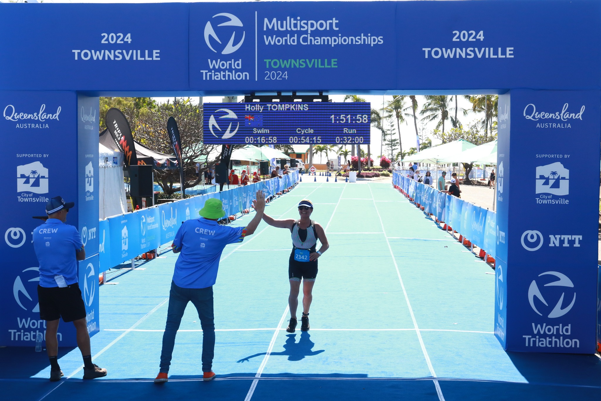Runner high-fives a crew member as she crosses the finish line of Townsville Triathlon Runner high-fives a crew member as she crosses the finish line of Townsville Triathlon