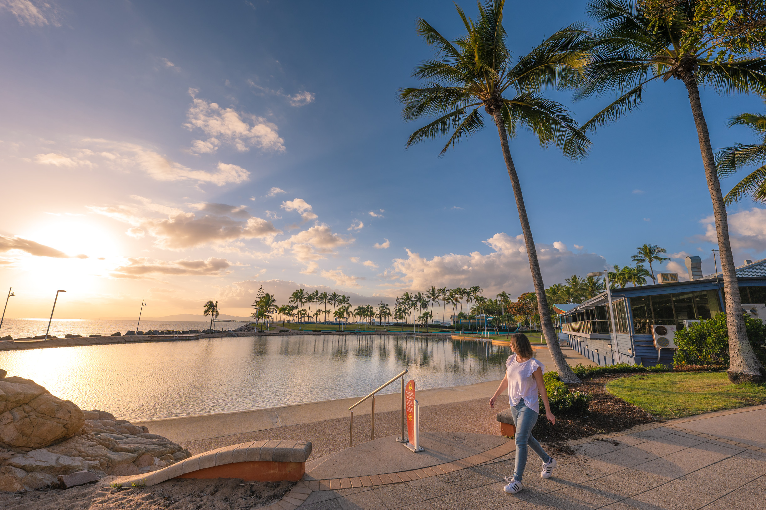 A woman strolls along The Strand at sunset