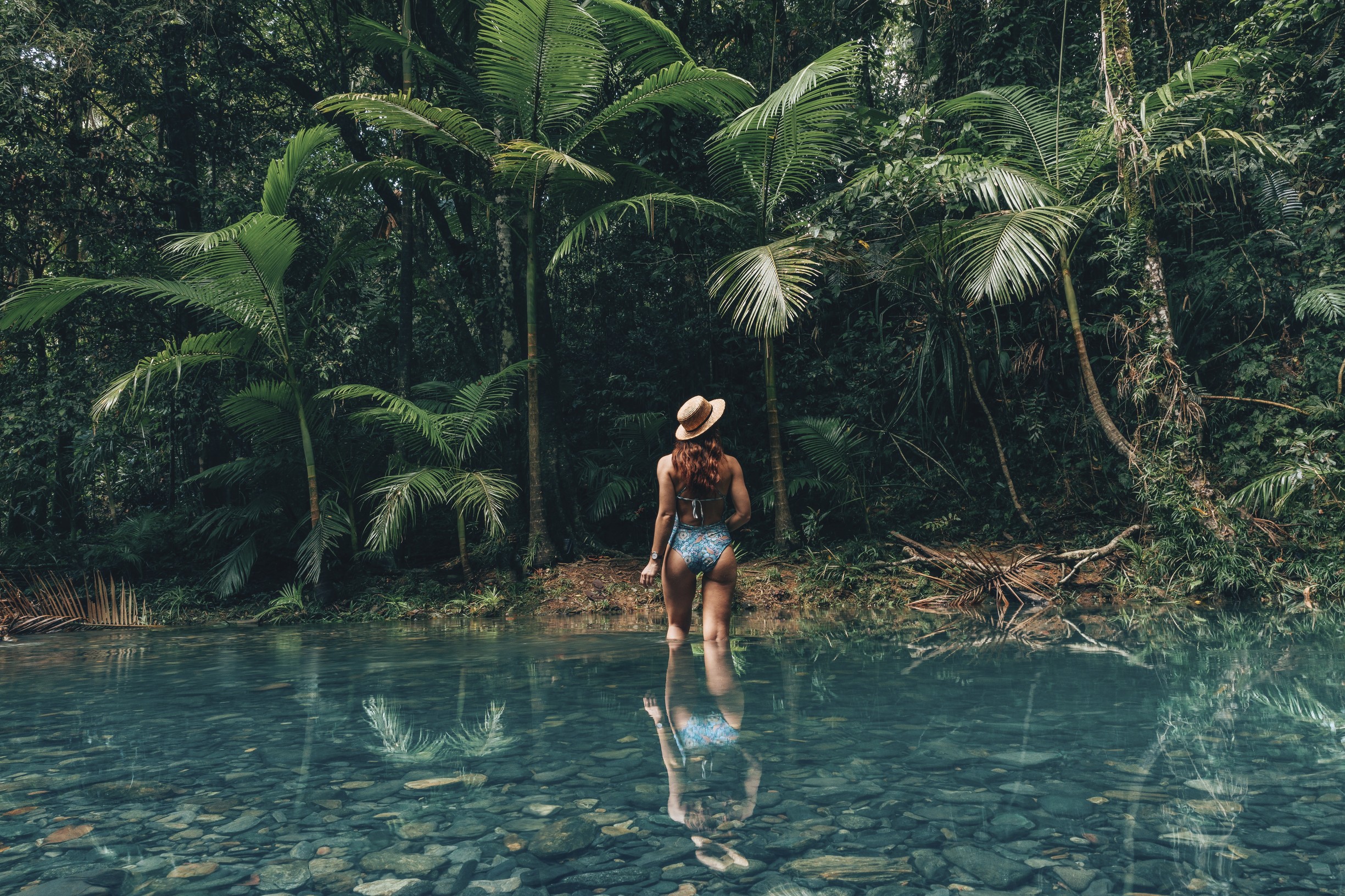 Female in swim suit walking into a rainforest hotel pool Female in swim suit walking into a rainforest hotel pool