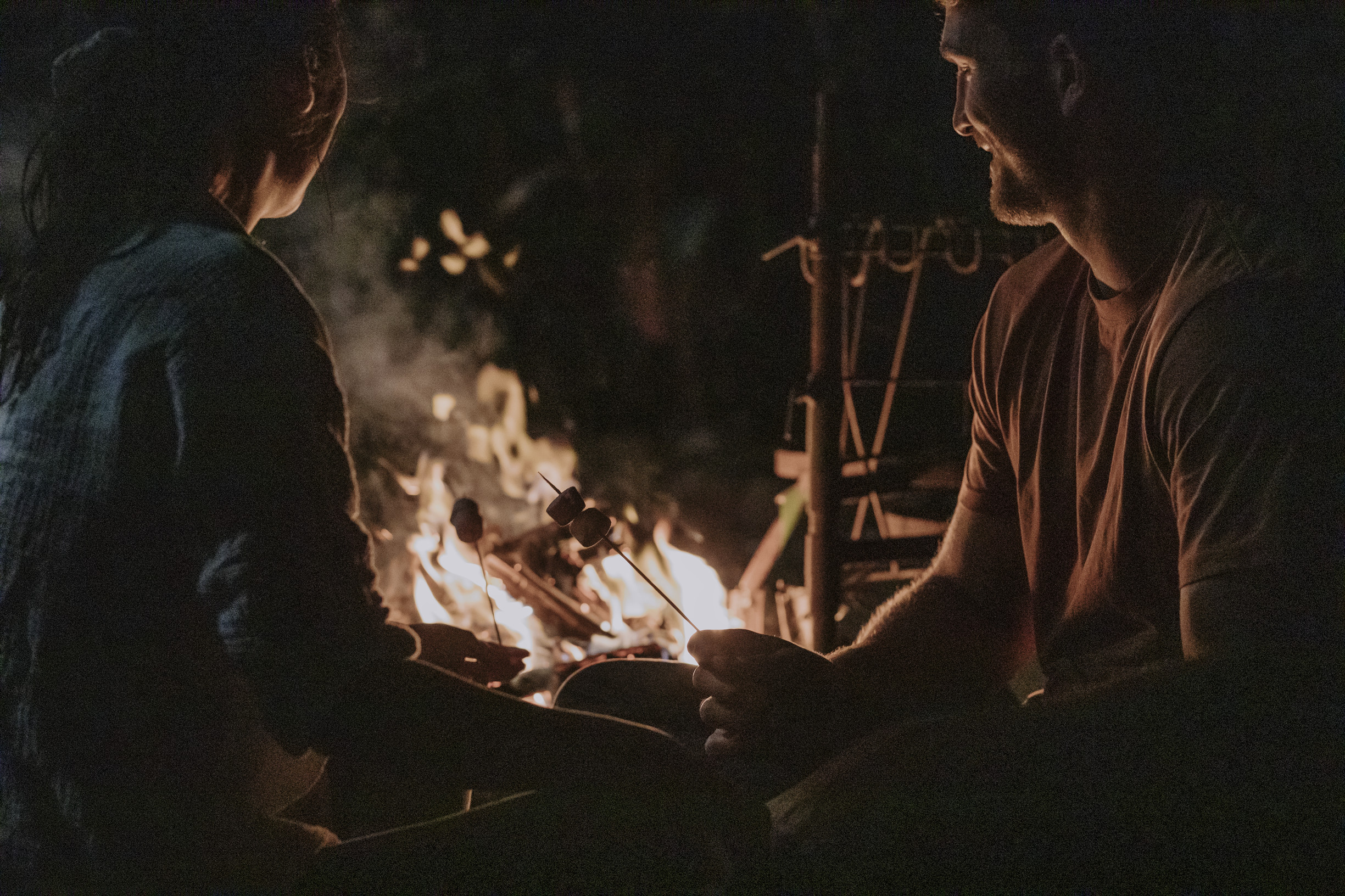 Two friends toasting marshmallows on a campfire at night Two friends toasting marshmallows on a campfire at night