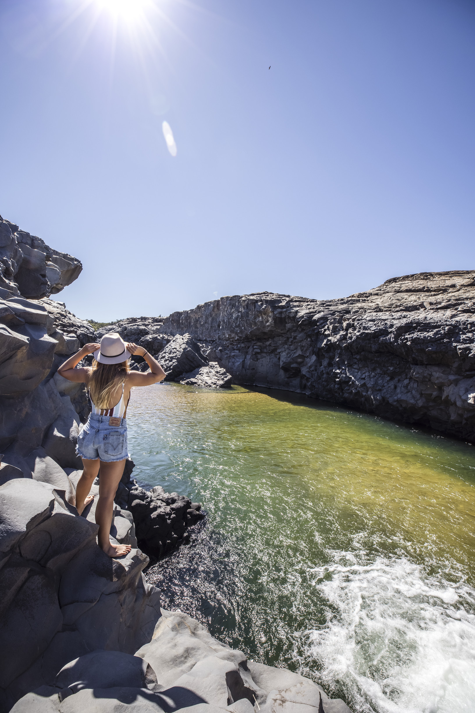 Woman stands on rocky edge at Copperfield Gorge, peering into the water