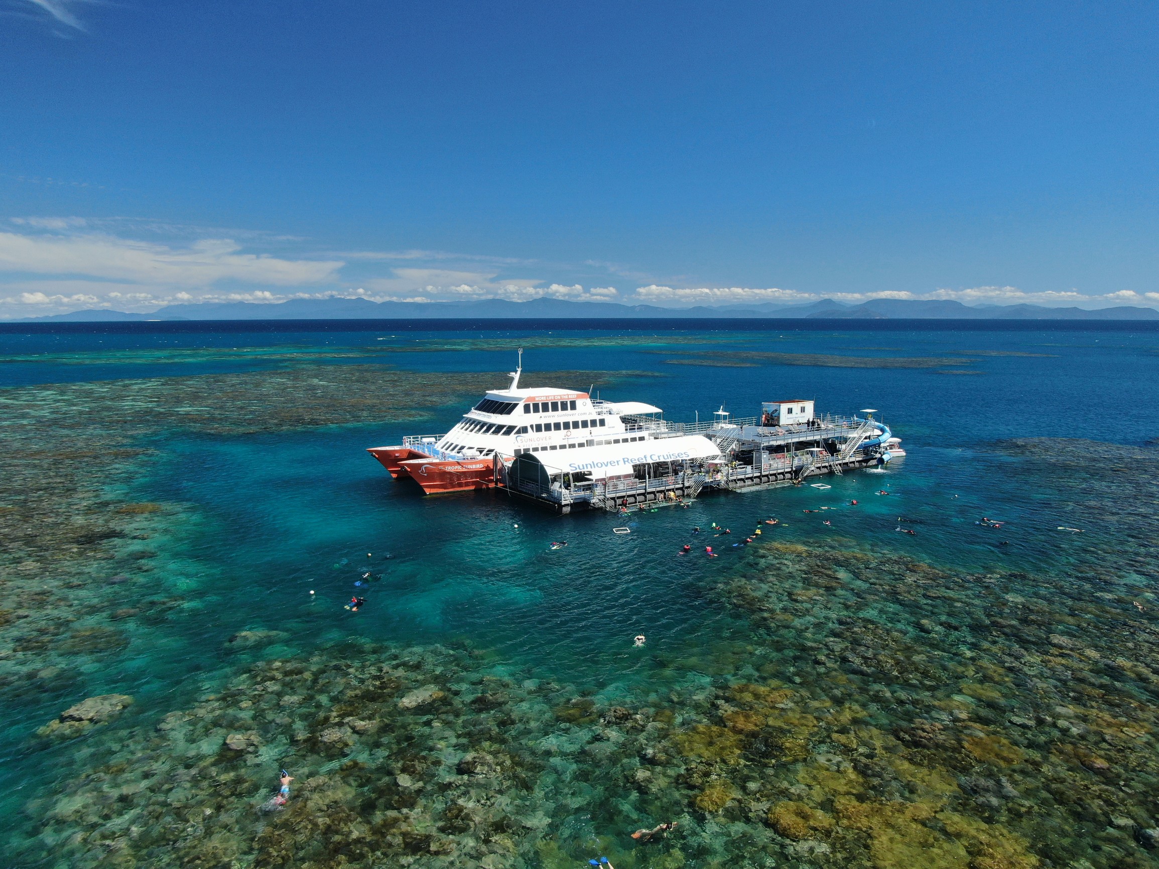 Aerial shot of Sunlover Reef Cruises moored at Moore Reef, surrounded by coral reef and snorkellers