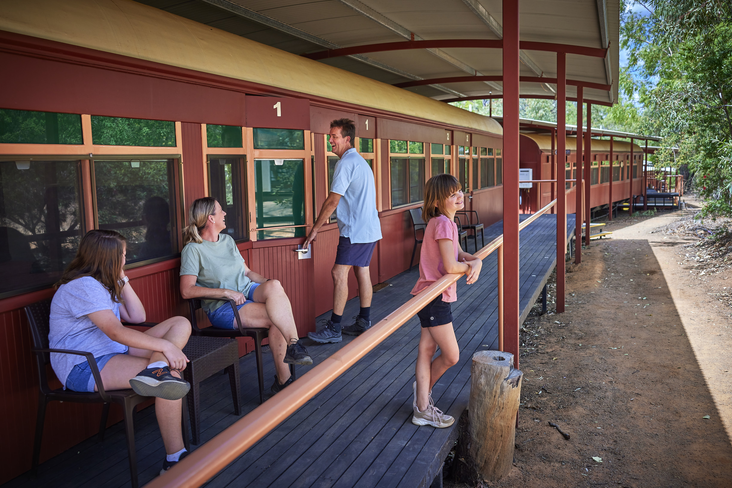 Family relaxing out the front of Undara Railway Carriage accommodation at Undara Experience