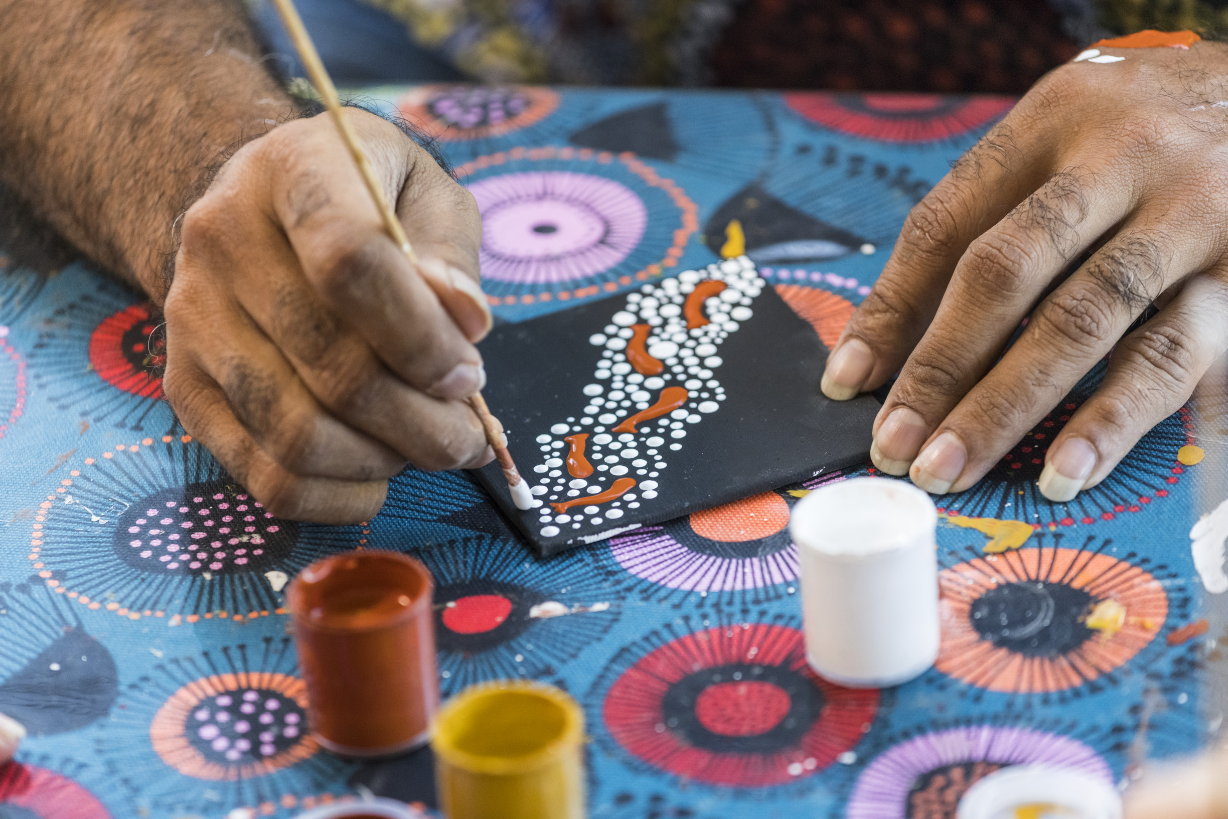 Close up of Indigenous artist, Brian "Binna" Swindley, hands as he demonstrates Aboriginal dot painting during an art class at Janbal Gallery, Mossman