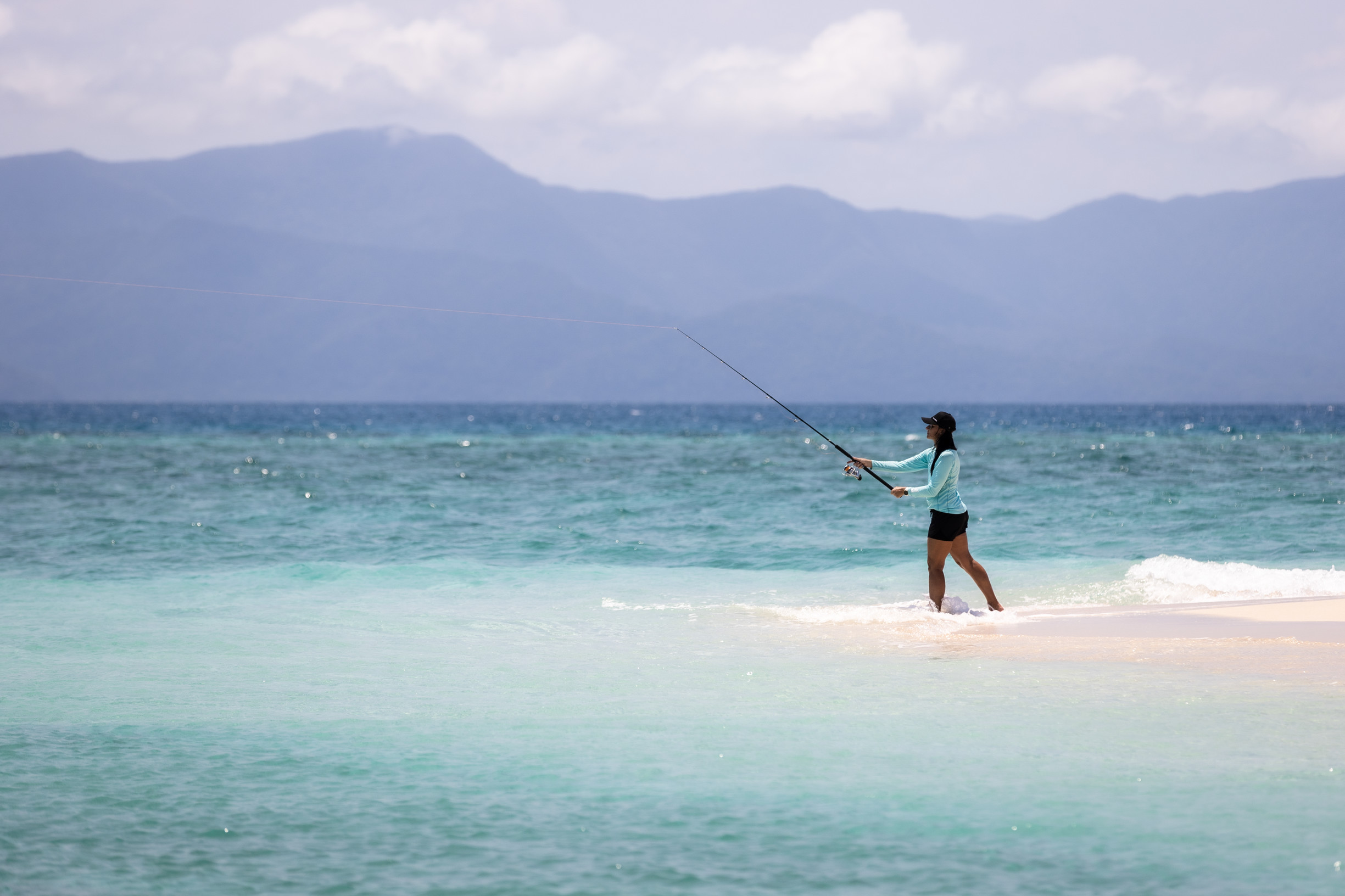 Lady fishing from a sand bank, while on a fishing charter