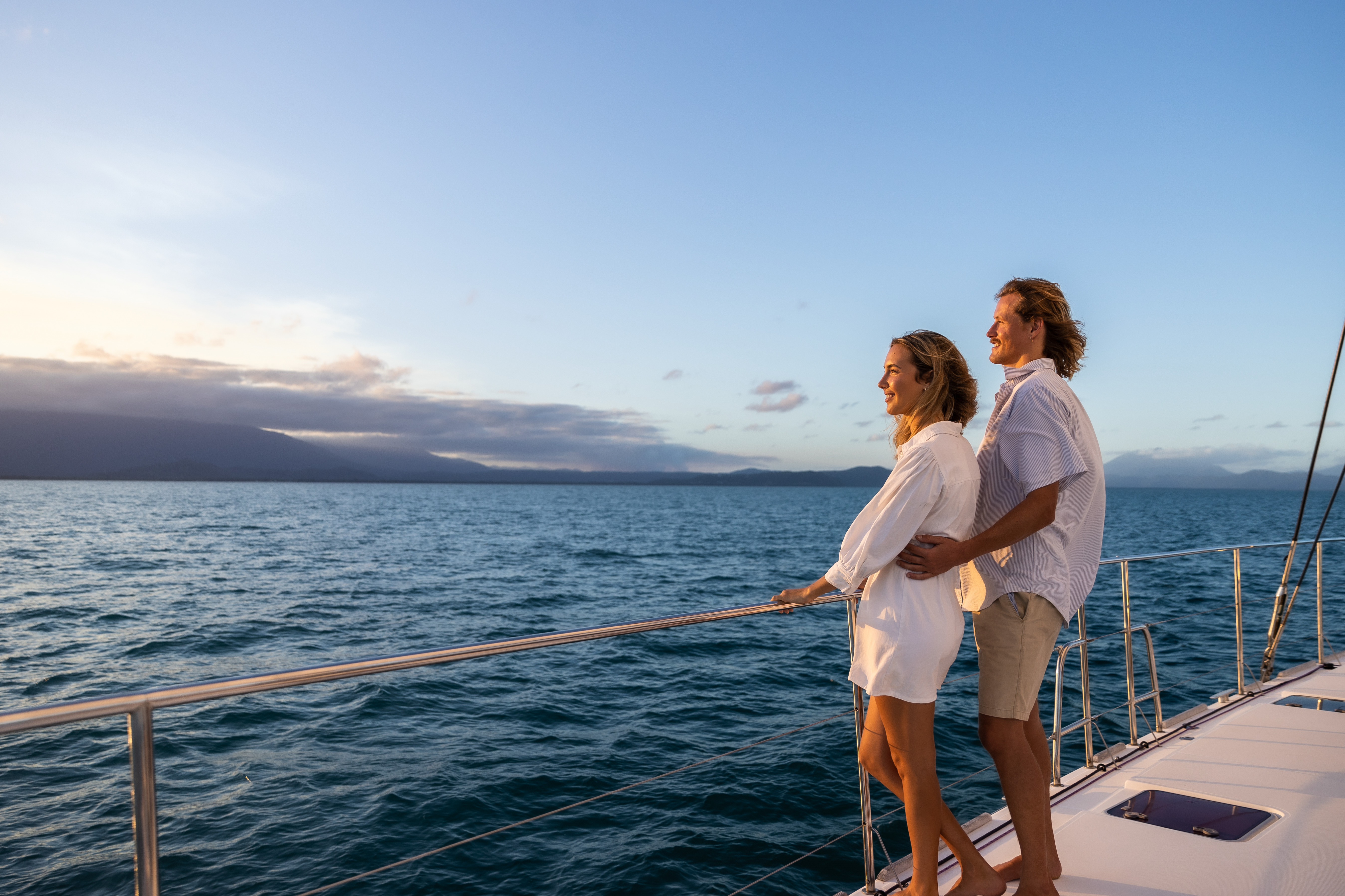 Couple looking out over the ocean as the sun is setting