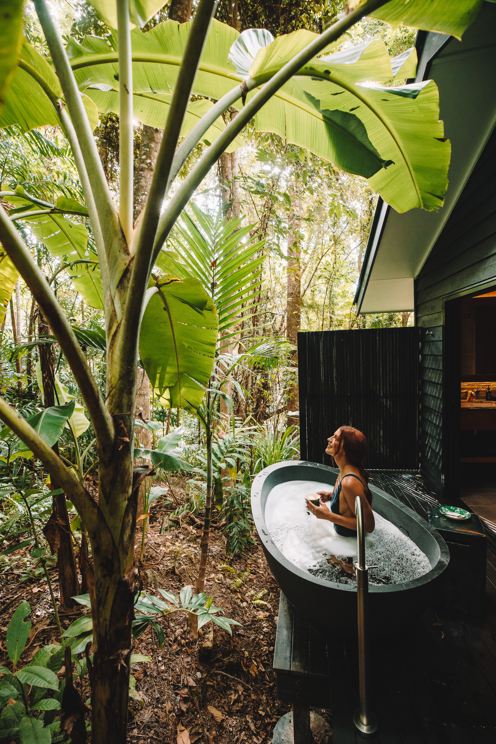 Lady relaxing in an outdoor bath among the rainforest