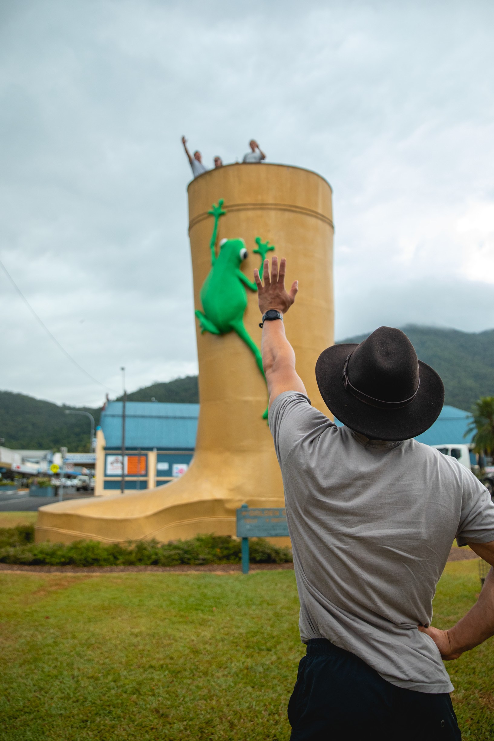Man waves to three friends standing at the top of The Golden Gumboot landmark in Tully
