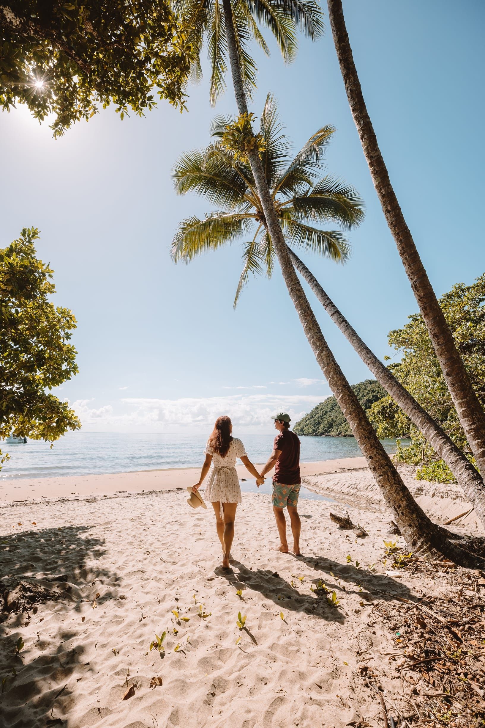 Couple walking onto the beach under the palm trees at Etty Bay