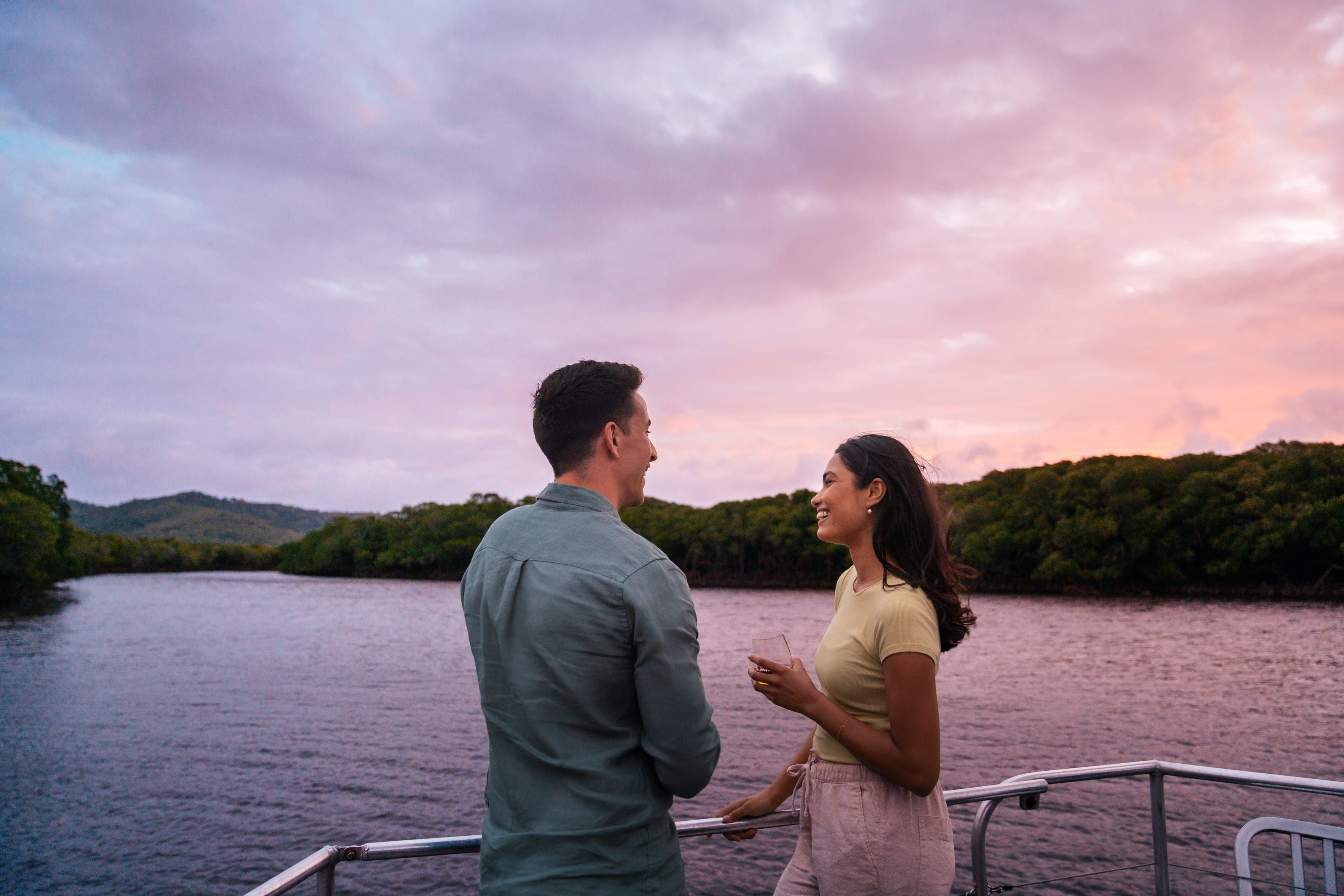 Couple enjoying a drink and sunset skies along the Endeavour River on a cruise with Riverbend Tours, Cooktown