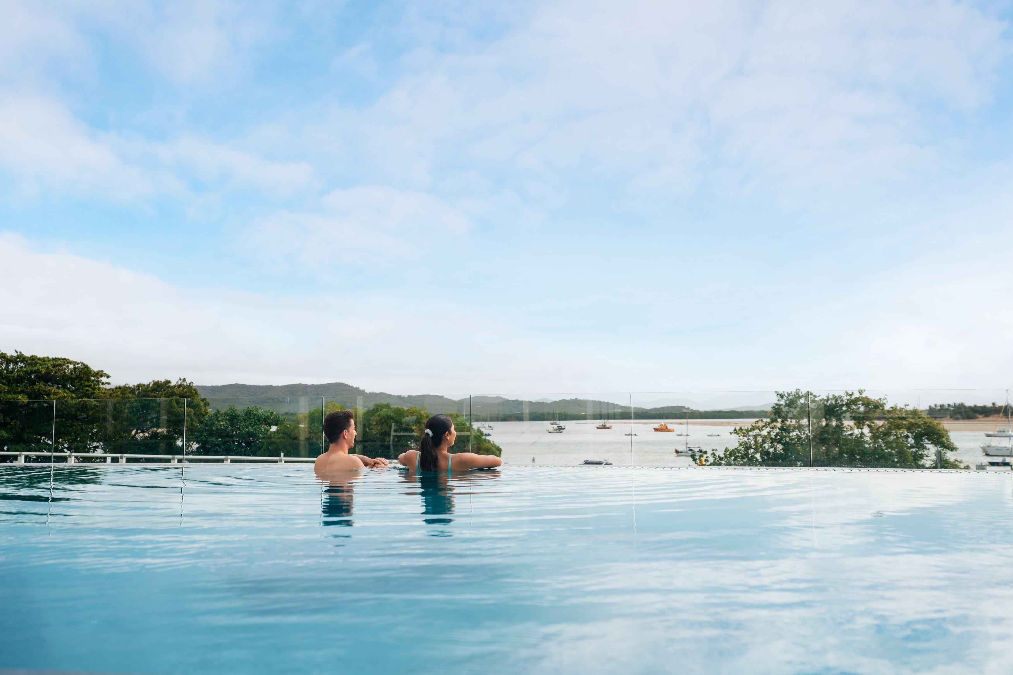 Couple relaxing in an infinity pool at The Seaview Cooktown, overlooking the harbour