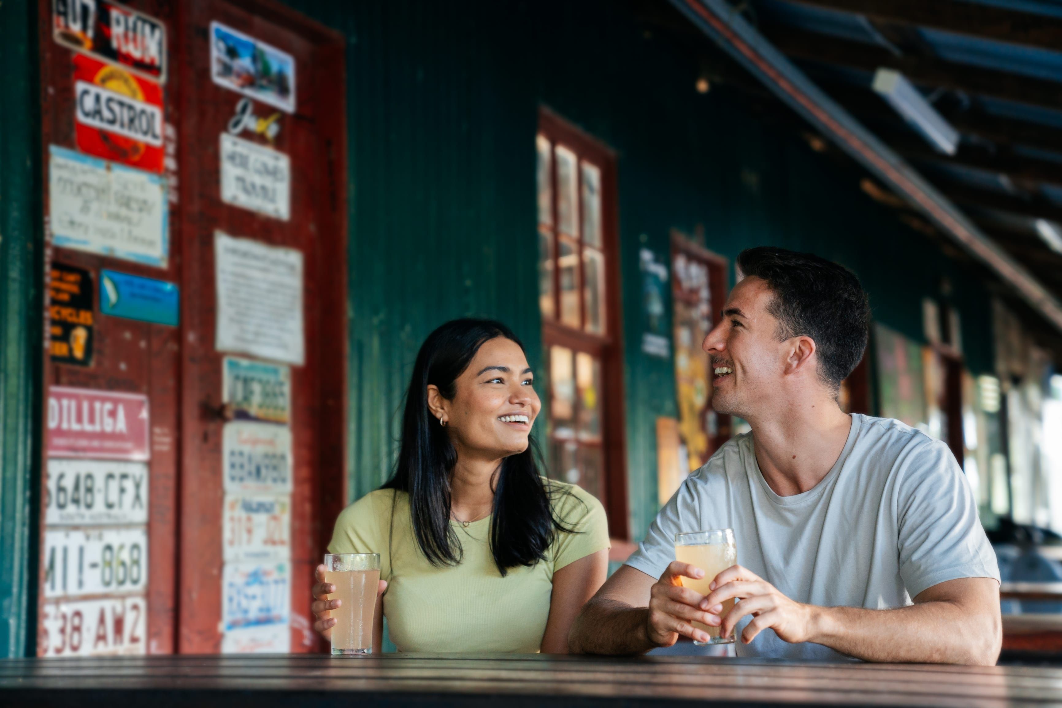 Couple enjoy a drink on the verandah of Lions Den Hotel, a historic pub Couple enjoy a drink on the verandah of Lions Den Hotel, a historic pub