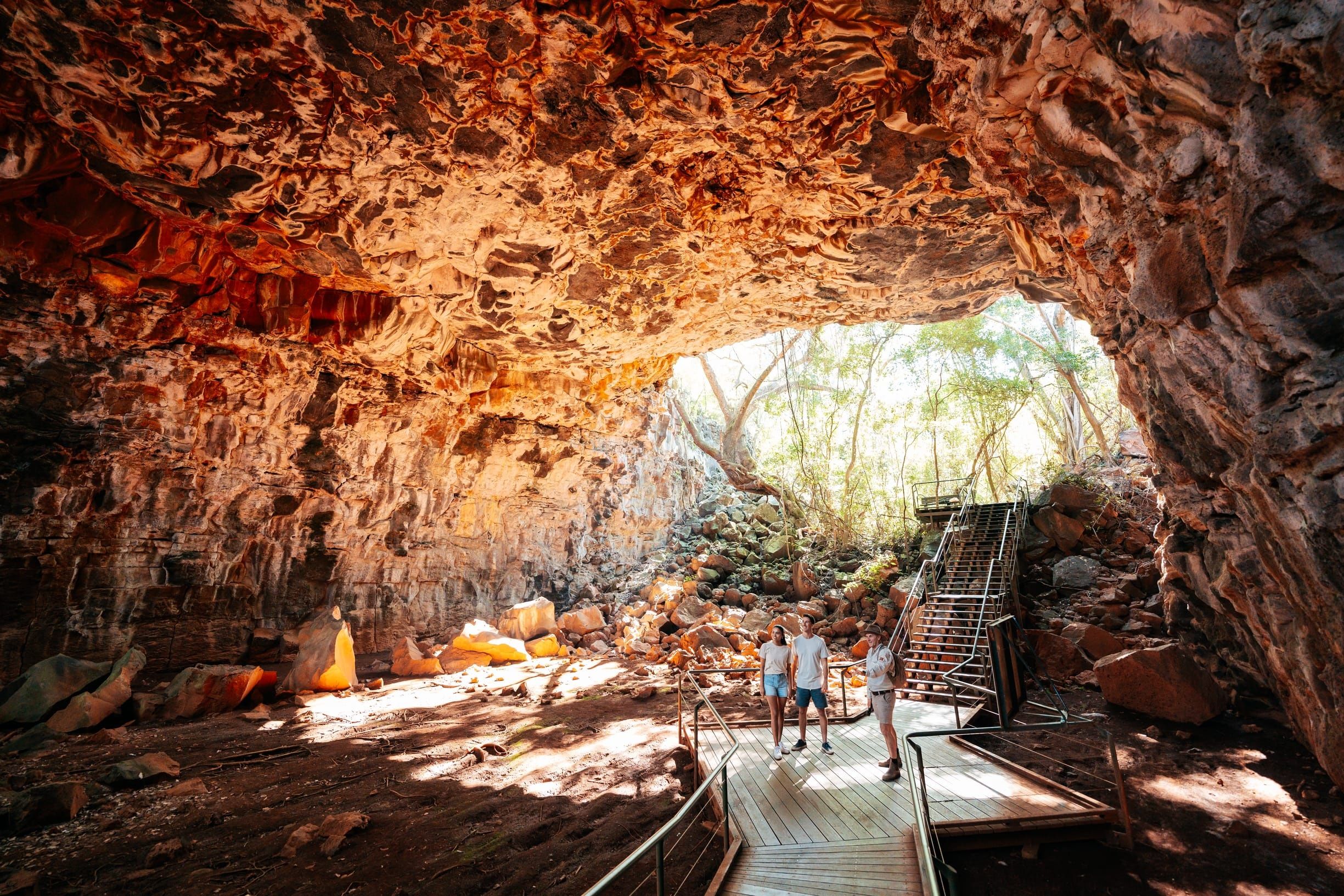 Couple and guide explore the lava tube cave system on the Archway Explorer Lava Tube Tour. at Discovery Resorts - Undara