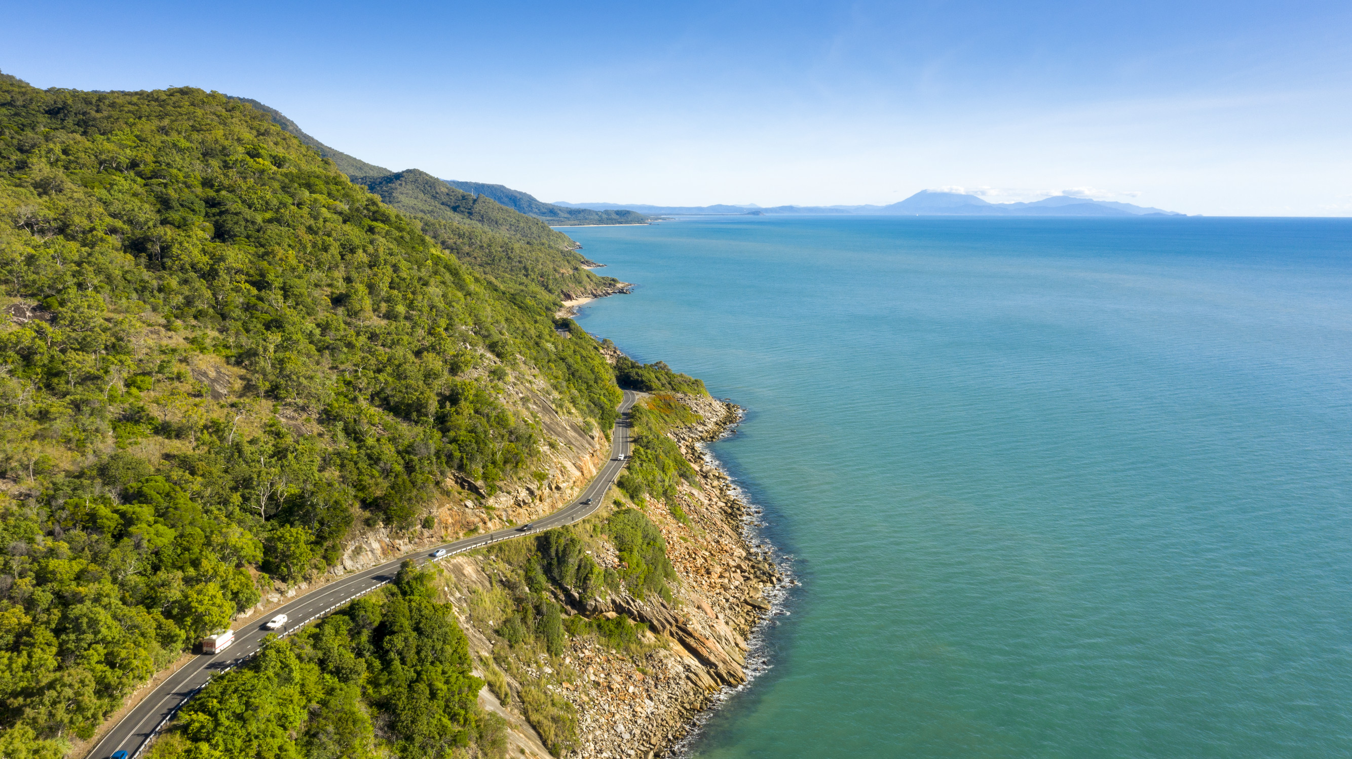 Cars drive along Great Barrier Reef drive, a highway that traces the tropical coastline