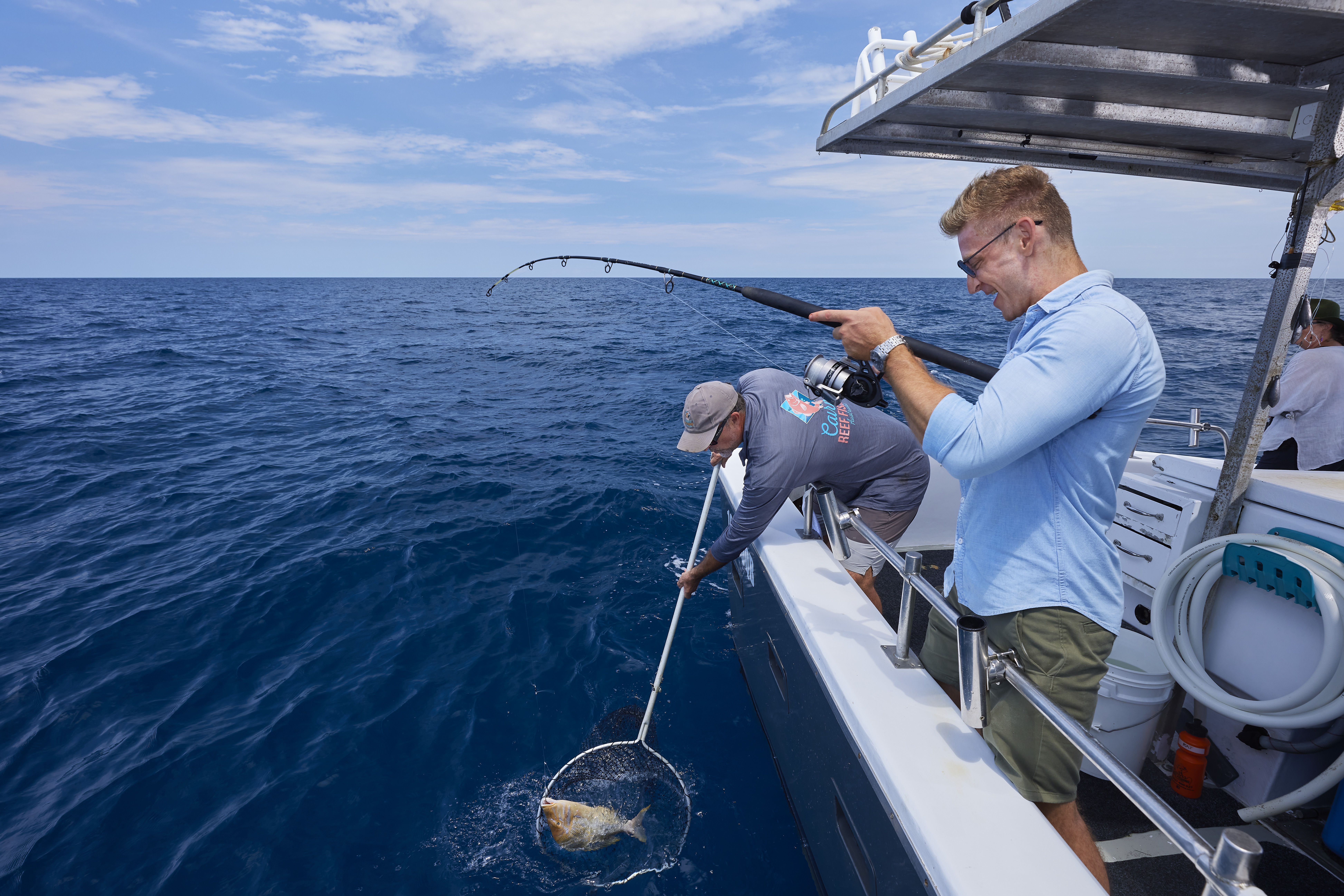 Man catching a fish on a Cairns Reef Fishing Charters boat Man catching a fish on a Cairns Reef Fishing Charters boat