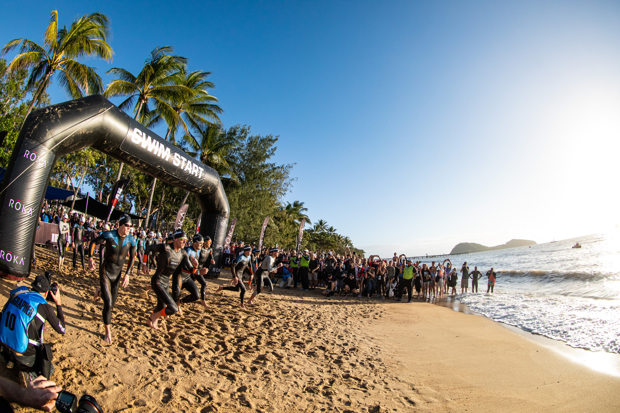 Cyclists riding coastal highway with Coral Sea and islands in the background, during Cairns Airport IRONMAN, Cairns