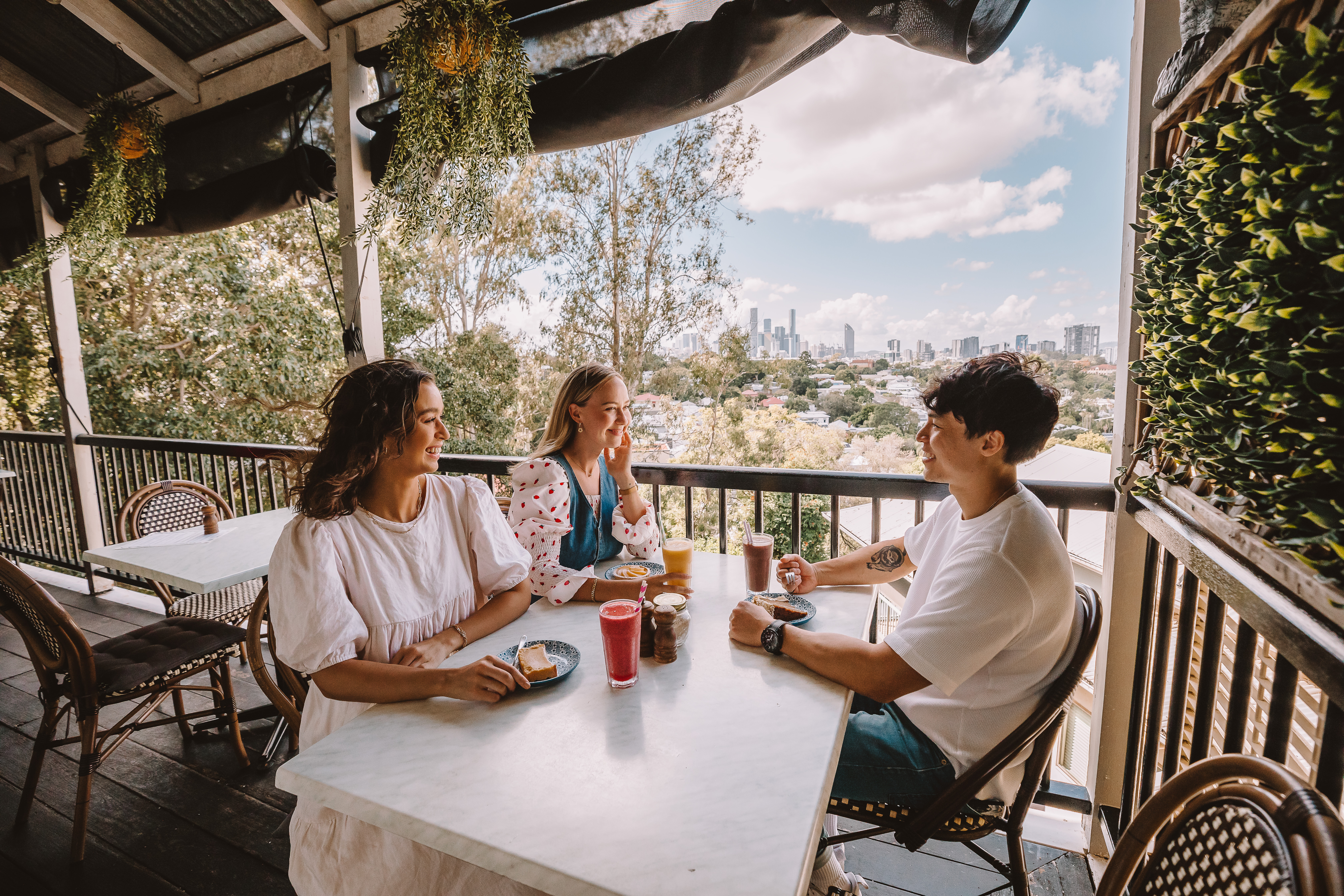 Group of friends having refreshments at Chapter IV, while looking out at the Brisbane City views
