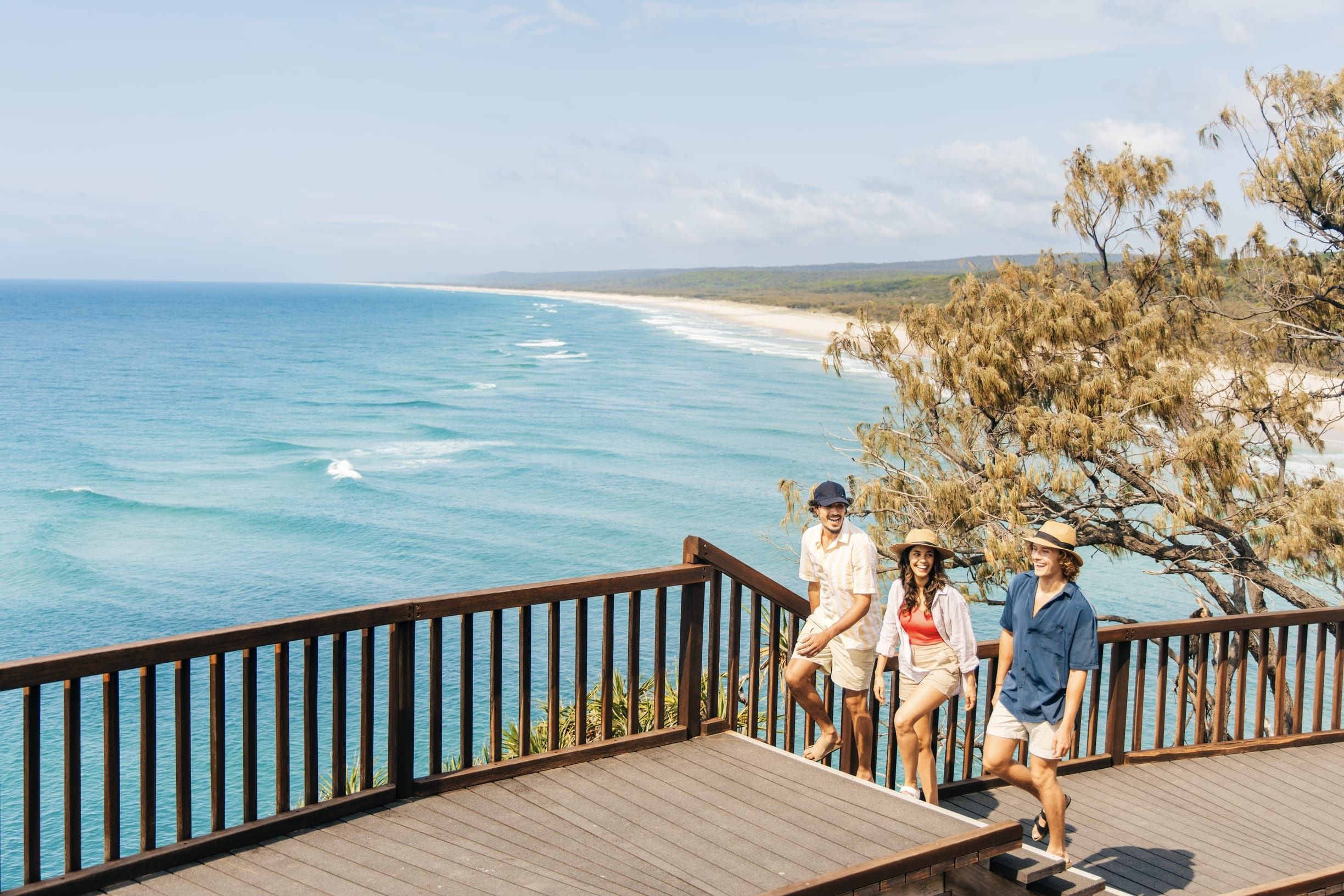 Three friends walk along cliffside coastal boardwalk