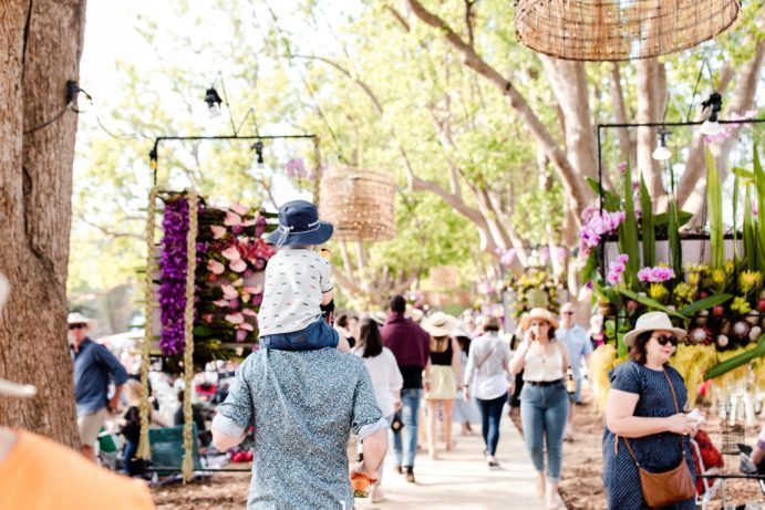 Father carries child on shoulders through a flower festival