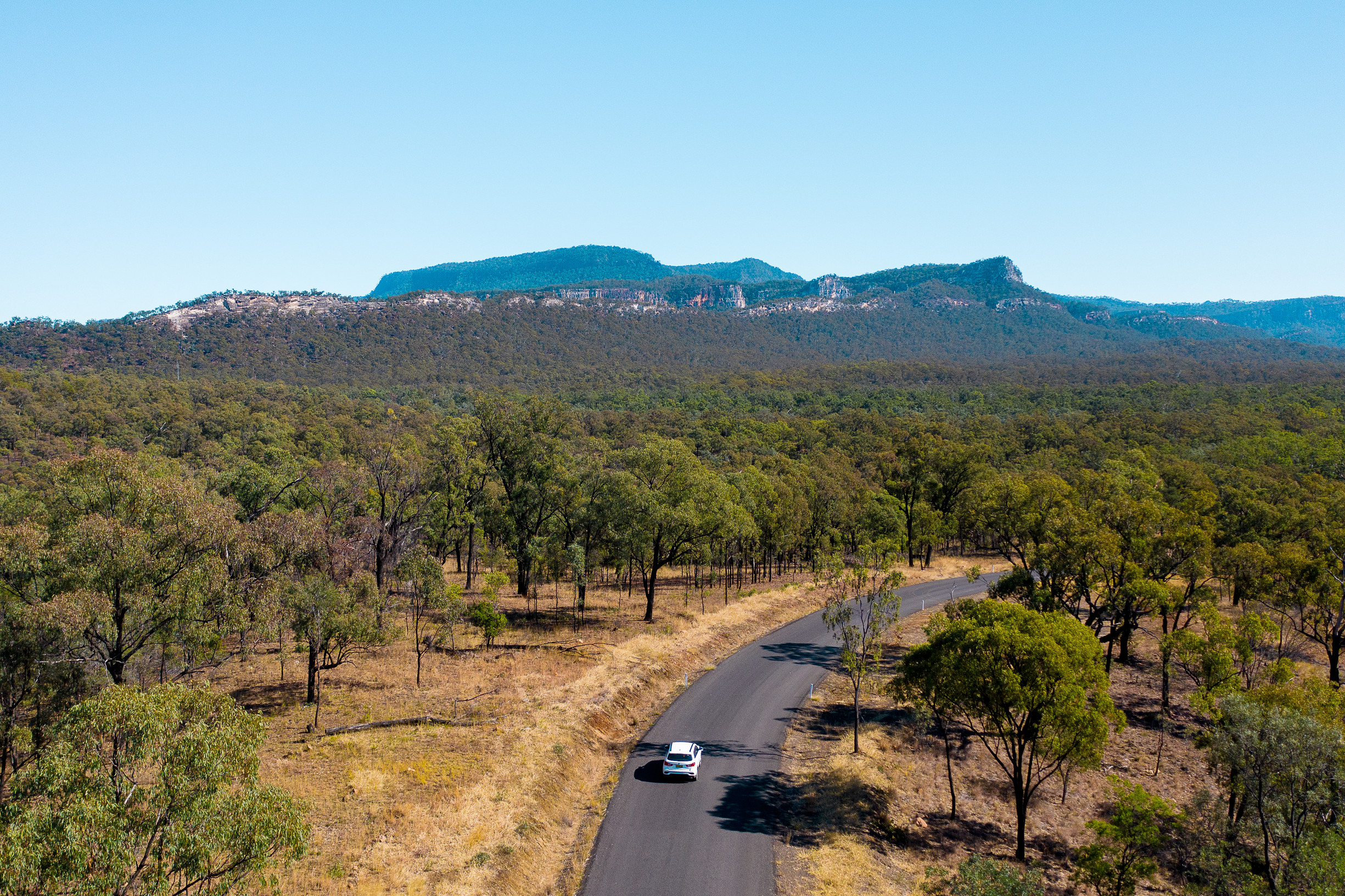 Car drives along sealed road approaching the scenery of Carnarvon National Park